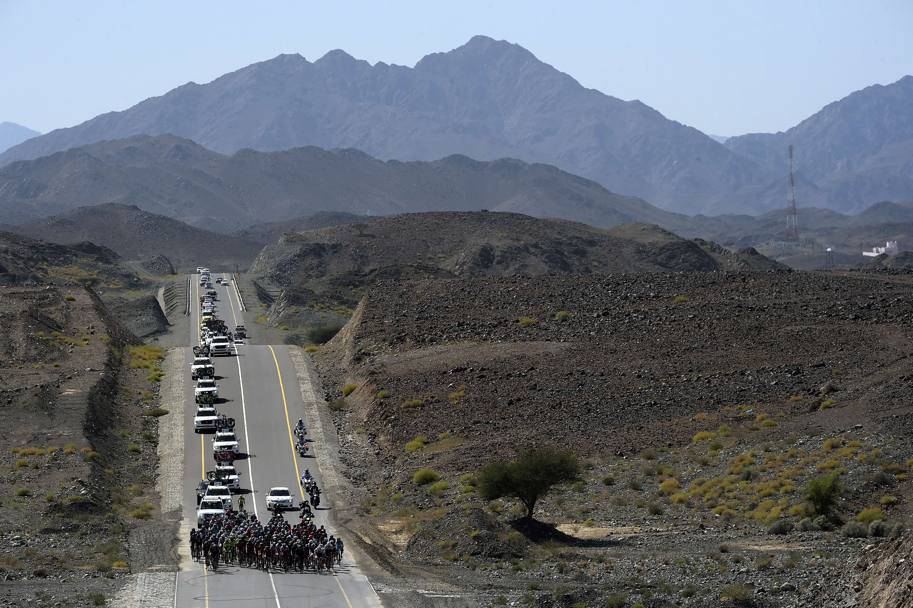 Alla ricerca dell’ombra perduta. Il gruppo si muove compatto sui saliescendi della terza tappa del Tour dell’Oman; intorno solo pietre roventi sullo sfondo montagne brulle (Afp)